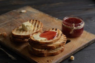 Toast bread with homemade strawberry jam and on rustic table with butter for breakfast or brunch.