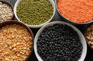 Koyu ahşap bir masa üzerinde çeşitli ham baklagiller.