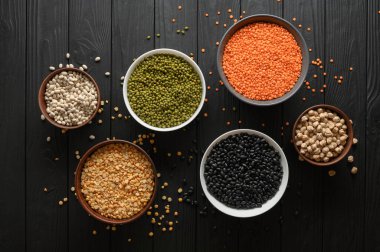 Koyu ahşap bir masa üzerinde çeşitli ham baklagiller.