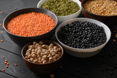 Koyu ahşap bir masa üzerinde çeşitli ham baklagiller.