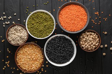 Koyu ahşap bir masa üzerinde çeşitli ham baklagiller.