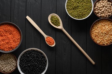 Koyu ahşap bir masa üzerinde çeşitli ham baklagiller.