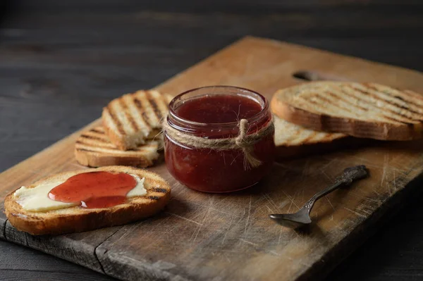 Toast bread with homemade strawberry jam and on rustic table with butter for breakfast or brunch.