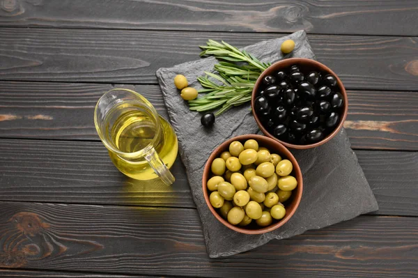 Black and green olives on a dark wooden rustic background.