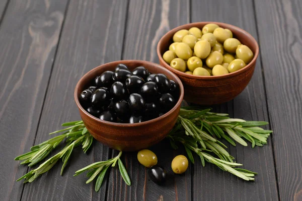 Black and green olives on a dark wooden rustic background.