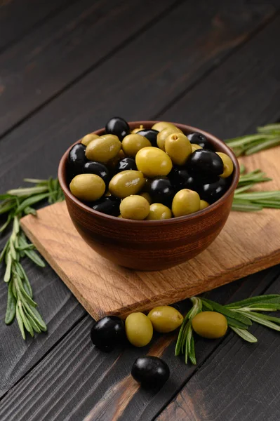 Black and green olives on a dark wooden rustic background.