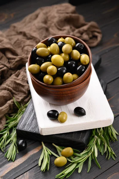 Black and green olives on a dark wooden rustic background.