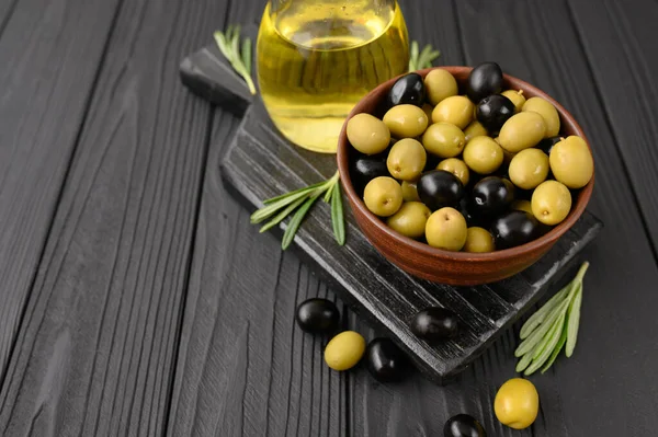 Black and green olives on a dark wooden black background.