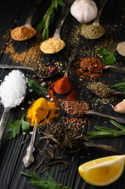 Koyu ahşap arka planda yemek pişirmek için çeşitli otlar ve baharatlar.