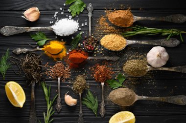 Koyu ahşap arka planda yemek pişirmek için çeşitli otlar ve baharatlar.