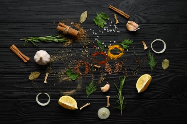 Koyu ahşap arka planda yemek pişirmek için çeşitli otlar ve baharatlar.