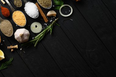 Koyu ahşap arka planda yemek pişirmek için çeşitli otlar ve baharatlar.
