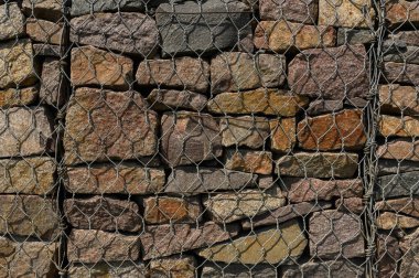 Taş duvar deseni. Metal ağ duvarının içindeki vahşi taş. Taş duvar arkaplanı ve dokusu