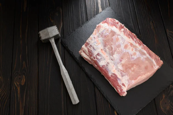 A large piece of pork loin on a rustic dark background.
