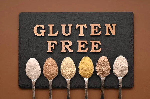 Gluten free text and spoons of various gluten free flour. Flat lay, top.