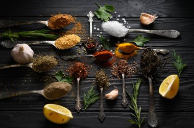 Koyu ahşap arka planda yemek pişirmek için çeşitli otlar ve baharatlar.