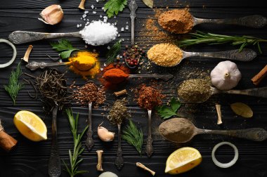 Koyu ahşap arka planda yemek pişirmek için çeşitli otlar ve baharatlar.