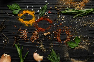 Koyu ahşap arka planda yemek pişirmek için çeşitli otlar ve baharatlar.