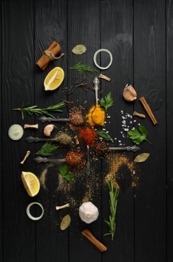 Koyu ahşap arka planda yemek pişirmek için çeşitli otlar ve baharatlar.