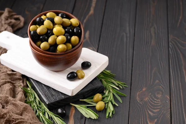 Black and green olives on a dark wooden rustic background.