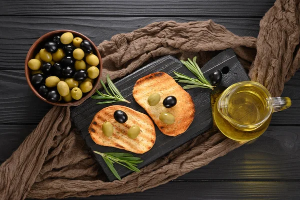 Black and green olives on a dark wooden black background.