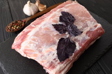 Kasvetli arka planda fesleğenli büyük bir parça domuz filetosu.