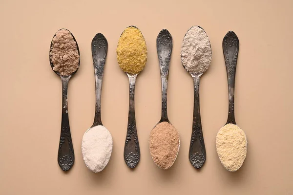 Gluten free text and spoons of various gluten free flour, almond buckwheat, rice, corn, oat, chickpea. Flat lay, top.