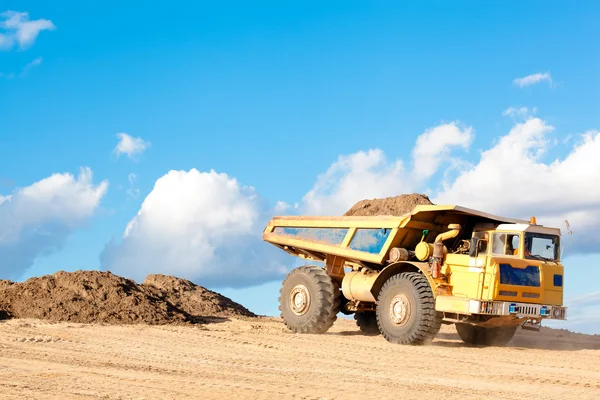 Heavy dump truck unloads soil on the sand — Stock Photo, Image