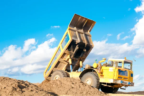 Caminhão de descarga pesada descarrega solo na areia — Fotografia de Stock