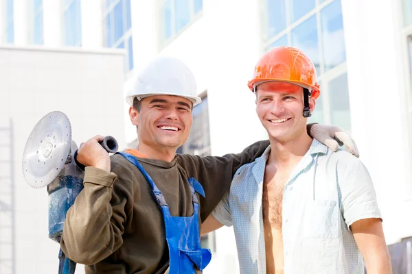 Twee positieve industriële arbeiders op de achtergrond van het gebouw — Stockfoto