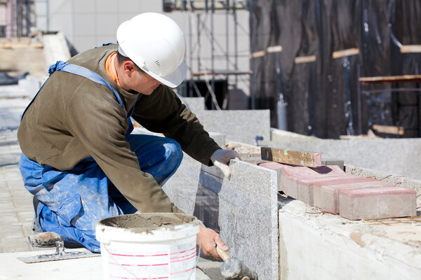 Tiler installing marble tiles at construction site