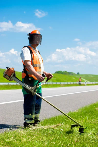 Straßengärtner mähen Gras entlang der Straße — Stockfoto