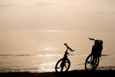 silhouetten van twee fietsen aan de kust