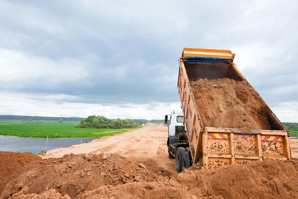 Volquete de descarga de arena durante las obras de carretera — Foto de Stock