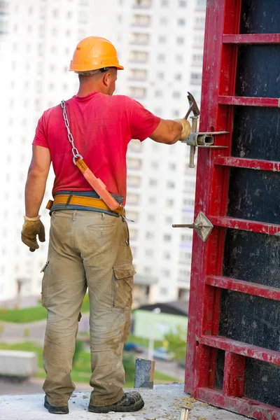 Bauarbeiter hämmert Bolzen für die Montage von Betonschalungen — Stockfoto