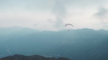 People flying paraglider over mountains
