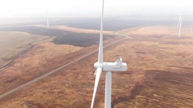 Wind turbine turns among field, propeller moves close up to the camera