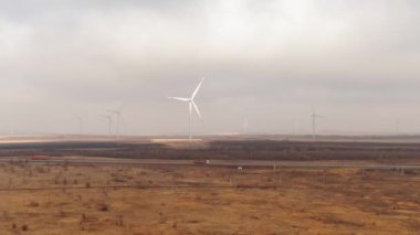 Wind turbines farm near the car road with a traffic