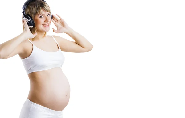 Gelukkig zwangere vrouw luisteren muziek in koptelefoon op wit wordt geïsoleerd — Stockfoto