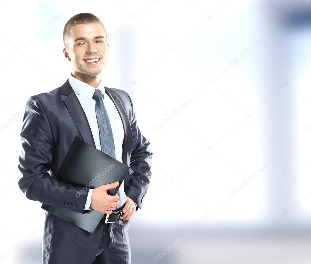 A happy businessman with blue folder posing in the office