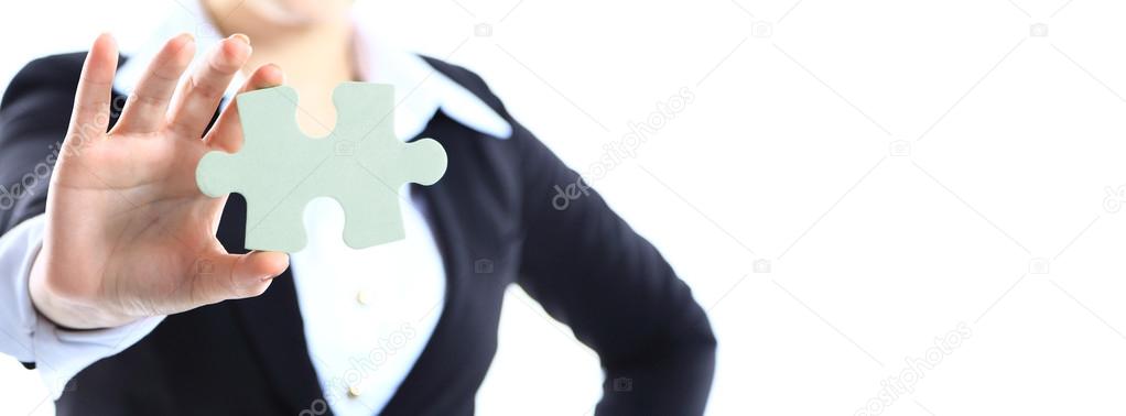 Cropped image of a woman in a business suit holding a single jigsaw piece