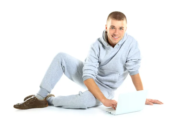 Красивый парень, работающий на ноутбуке и сидящий на полу, изолированный на белом фоне — стоковое фото