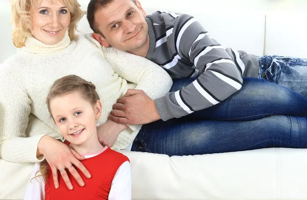 Family with children sitting on white leather sofa — Stock Photo, Image