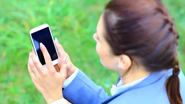 Mujer sosteniendo la mano teléfono inteligente contra el fondo verde primavera — Foto de Stock