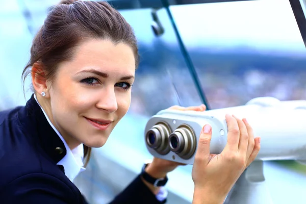 Femme d'affaires regarde à travers le télescope sur le bâtiment de la ville — Photo