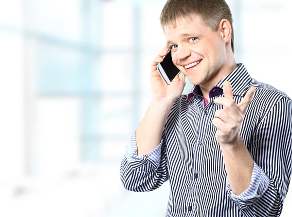 Alegre hombre de negocios en la oficina brillante mirando a la cámara mientras tiene una llamada telefónica — Foto de Stock