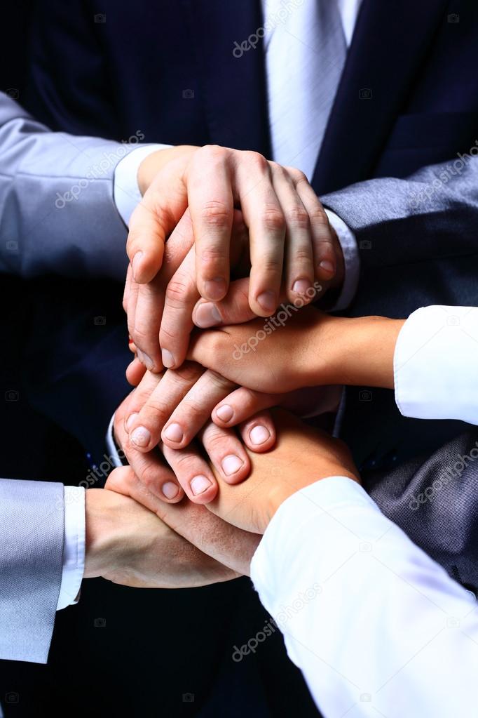 Diverse group of workers with their hands together in form of teamwork
