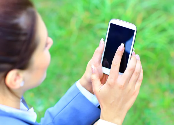 Mujer sosteniendo la mano teléfono inteligente contra el fondo verde primavera — Foto de Stock