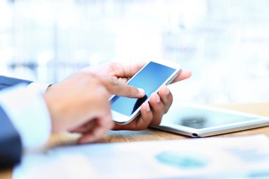 Modern cihazlar, dijital tablet bilgisayar ve cep telefonuyla çalışan genç işadamı.