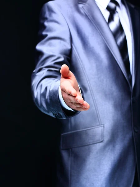 A businessman offering to shake your hand - isolated on a dark background — Stock Photo, Image